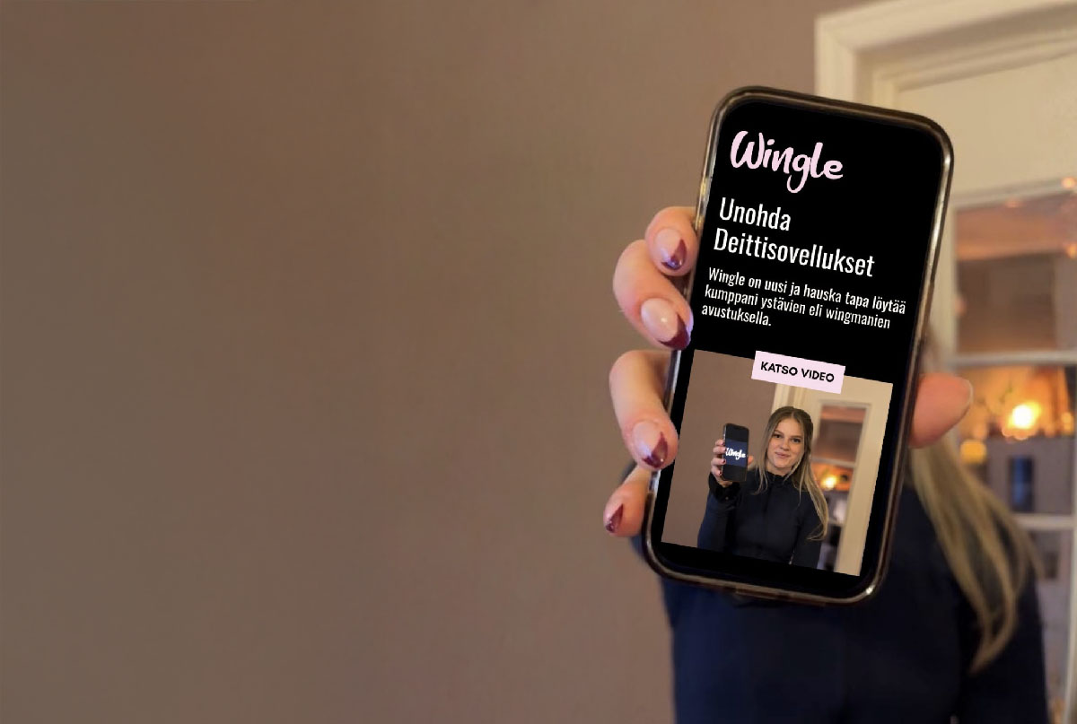 Nainen pitää kännykkää, jossa Wingle-sovellus